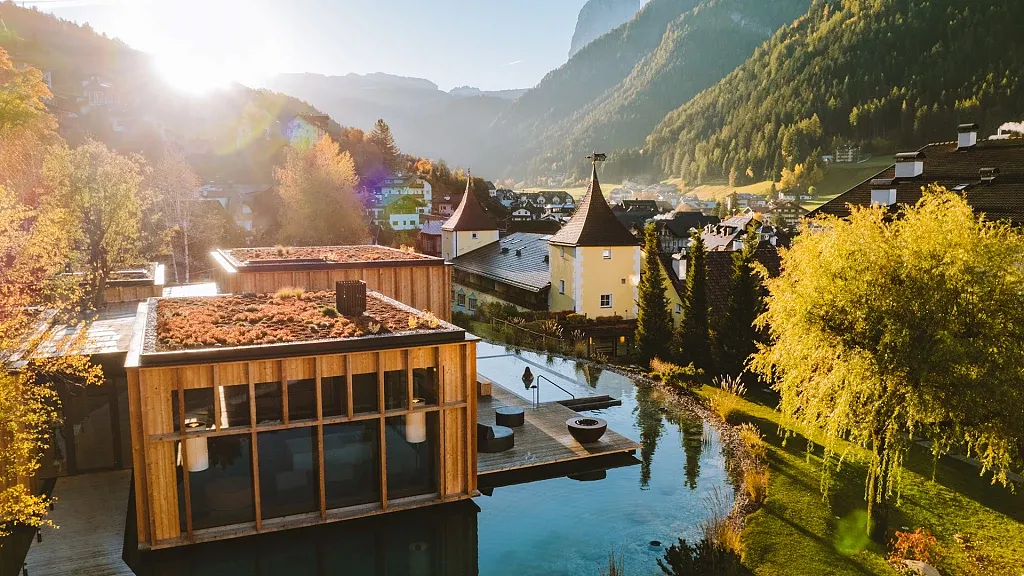 Sauna and small lake in the garden in autumn at ADLER Spa Resort Dolomiti